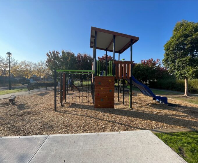 Playground with blue slide, colourful rock climbing wall and a climbing net.