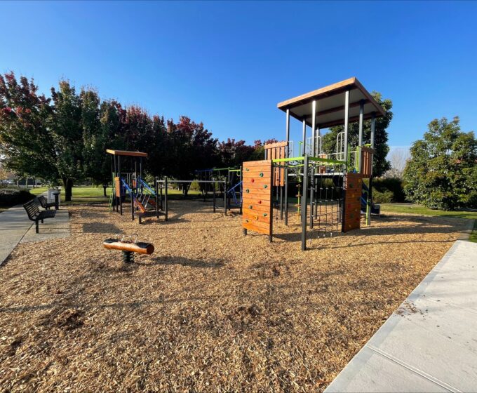 Playground with blue slide, colourful rock climbing wall and a climbing net.