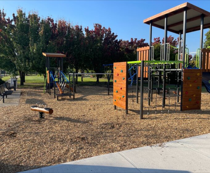 Playground with blue slide, colourful rock climbing wall and a climbing net.